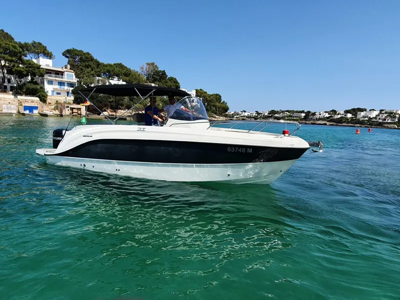 Die Quicksilver 805 „Vida Loca“ vor Pinien und weißen Häusern in einer Bucht
