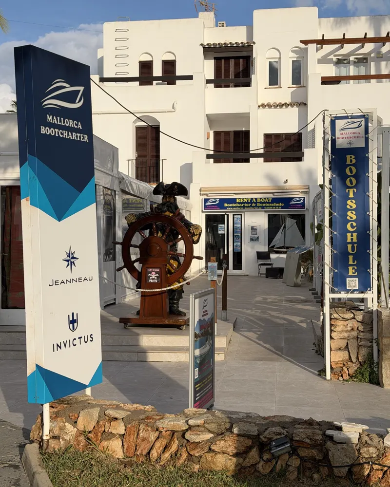 The Mallorca Bootcharter office in Cala d'Or with the pirate figure at the ship's wheel and the display boards in front of the door
